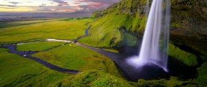 Waterfall to the right, green fiellds to the left. Summer in iceland